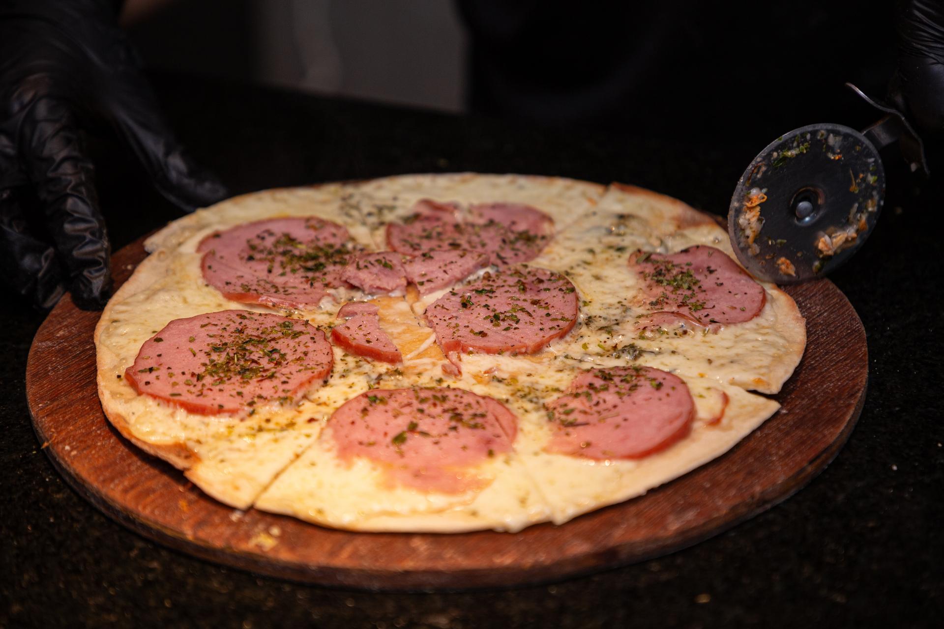 Pizza calabresa sendo cortada